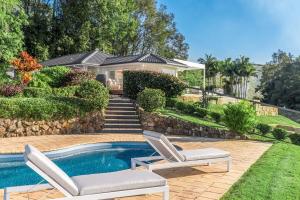 a house with a swimming pool and two lounge chairs at The Bower - Byron Hinterland in Teven