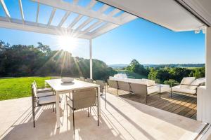 a patio with a table and chairs and the sun at The Bower - Byron Hinterland in Teven