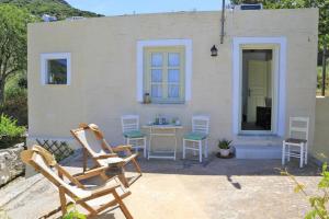 a patio with chairs and a table in front of a house at Oak Farm Guest House Junior in Andros