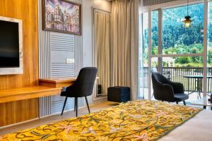 a bedroom with a bed and chairs and a balcony at Asal Riverside Pahalgam in Pahalgām