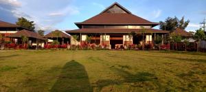 a large house with a long shadow on the grass at Tridalam Resort in Bangalore