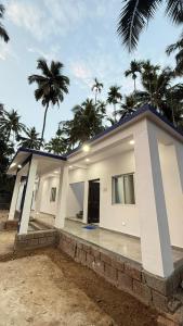 a small white house with palm trees in the background at Hotel calm resort in Murud