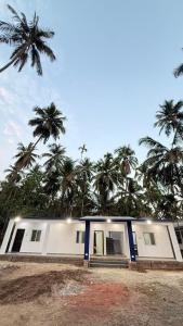 a white house with palm trees in the background at Hotel calm resort in Murud