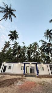 a white house with palm trees in the background at Hotel calm resort in Murud