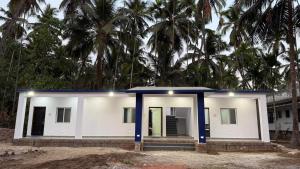 a white house with palm trees in the background at Hotel calm resort in Murud +1 photo
