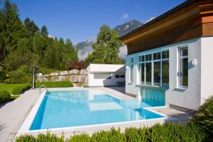 a swimming pool in a yard next to a house at Relax- & Wanderhotel Poppengut in Hinterstoder