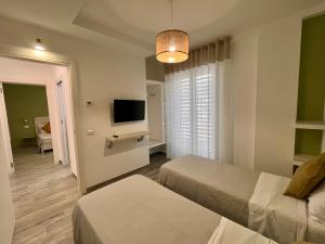 a hotel room with two beds and a flat screen tv at Dimora del Corso - Rooms in Mattinata +66 photos