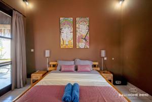 a bedroom with a bed with pink pillows and two paintings at villa TOYA NING in Ungasan