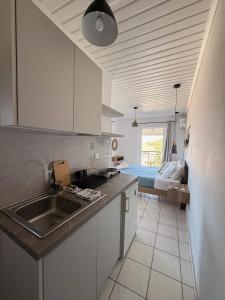 a kitchen with white cabinets and a sink and a bed at Vaso Alykanas Studios in Alikanas +58 photos