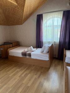 a bedroom with a bed and a window with purple curtains at Otel delfin in Karolino-Buhaz