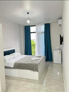 a bedroom with a bed with blue curtains and a window at Relax inn in Kobuleti