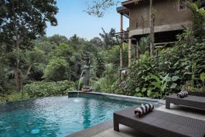 a swimming pool with two chairs and a water fountain at Harsa Sanctuary by GenuineHost in Ubud +60 photos