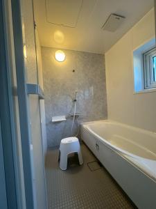 a bathroom with a toilet and a tub and a stool at Guest house LIA1 in Abashiri +20 photos