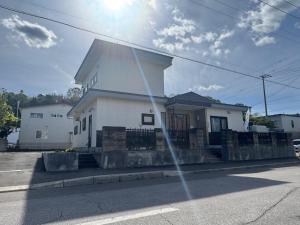 a white house on the side of a street at Guest house LIA1 in Abashiri