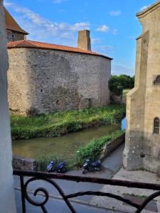 two motor scooters parked next to a river next to a building at Le Logis du Donjon 2 in Les Herbiers