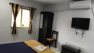 a bedroom with a bed and a tv and a chair at Hotel Radha krishna in Neral
