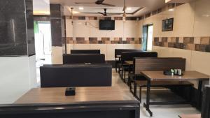 a dining room with tables and chairs and a tv at Hotel Radha krishna in Neral