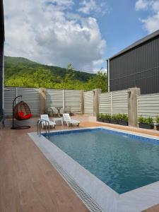 a swimming pool with two white chairs next to a building at Pine Barnhouse Family in İsmayıllı