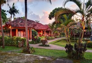 a house with palm trees in front of it at Lovina Beach Hotel in Lovina