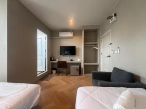 a bedroom with a bed and a desk with a tv at The Elegant Bangna Suvarnabhumi in Ban Map Prasoe