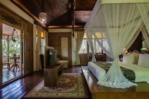 a bedroom with a bed with curtains and a tv at Plataran Komodo Resort & Spa - CHSE Certified in Labuan Bajo +197 photos