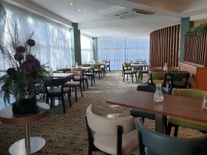 a restaurant with tables and chairs and flowers on the wall at Legacy Preston International Hotel in Preston