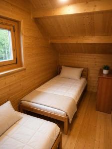 a room with two beds in a log cabin at Domek z BALIA OGRODOWA in Dłużec