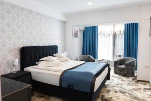 a bedroom with a large bed with blue and white sheets at Hotel Sallaris Monteoru in Sărata-Monteoru