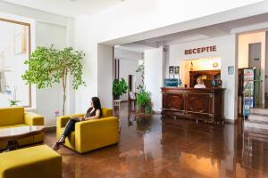 a woman sitting on a yellow couch in a lobby at Hotel Sallaris Monteoru in Sărata-Monteoru