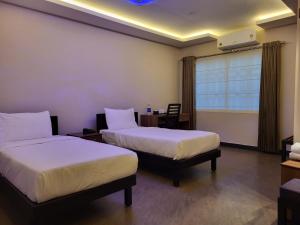 a hotel room with two beds and a window at Hotel Grand Vista in Cochin