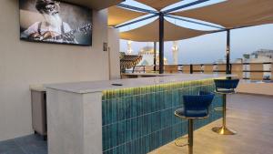 a bar with blue chairs and a tv on a roof at Blue Stone H in Madaba