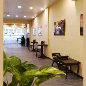 a waiting room with tables and chairs and plants at Twins Hotel in Jakarta