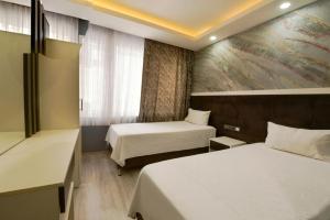 a hotel room with two beds and a painting on the wall at Denizli Hotel in Istanbul