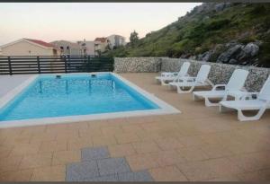 a swimming pool with white chairs and a swimming pool at Apartman Anela in Ivanica