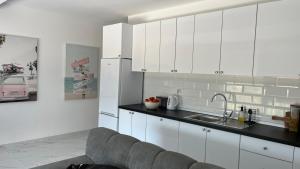 a kitchen with white cabinets and a gray couch at Apartman Anela in Ivanica