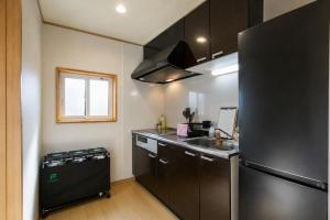 a kitchen with a black refrigerator and a sink at バンビホーム青森中央 in Aomori