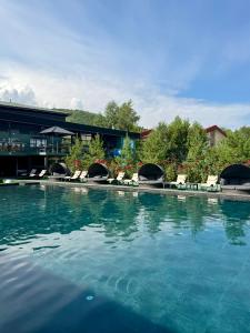 a large swimming pool with chairs and a building at Mirali Resort in Almaty