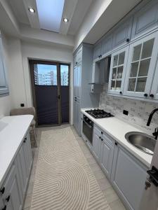a kitchen with white cabinets and a sink and a stove at Top1 Gardens Residents in Tashkent