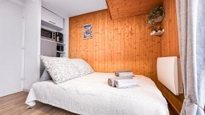 a small bedroom with a bed and a wooden wall at Vue Lac Léman & Télécabine à 1 minute in Thollon
