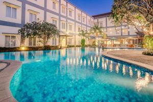 a swimming pool in front of a building at Hotel Puri Indah & Convention in Tjakranegara