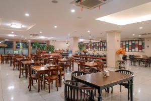 a restaurant with wooden tables and chairs and a bar at Hotel Puri Indah & Convention in Tjakranegara