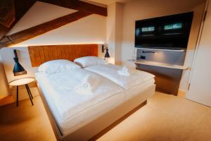 a bedroom with a large white bed and a television at Die Burg - Kurfürstlich Flämisch in Bad Belzig