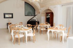 a dining room with tables and chairs and a piano at Masseria La Vecchia Lamia in San Vito dei Normanni