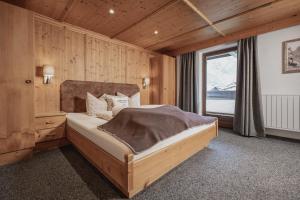 a bedroom with a bed and a large window at Appartements Alpenrose in Längenfeld