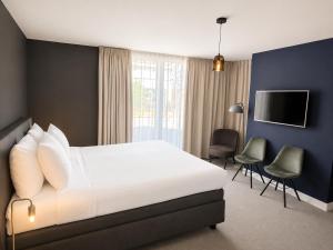 a bedroom with a bed and chairs and a tv at Boutique Hotel Zaan in Zaandijk
