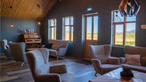 a waiting room with chairs and a table and windows at Fjalladýrð Hotel in Modrudalur