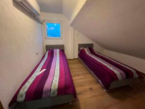 two beds in a small room with a window at Apartman Kastel in Travnik