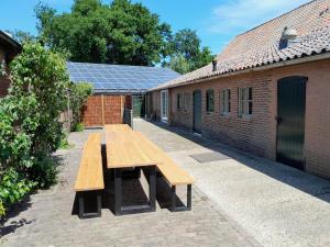 a wooden picnic table in front of a building with solar panels at De Spaanse Ruiter in Leusden