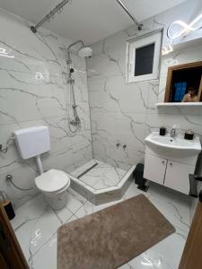 a white bathroom with a toilet and a sink at Apartman Kastel in Travnik