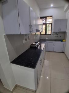a kitchen with white cabinets and a black counter top at Guruji Homestay Near UPES Collage in Jhājra